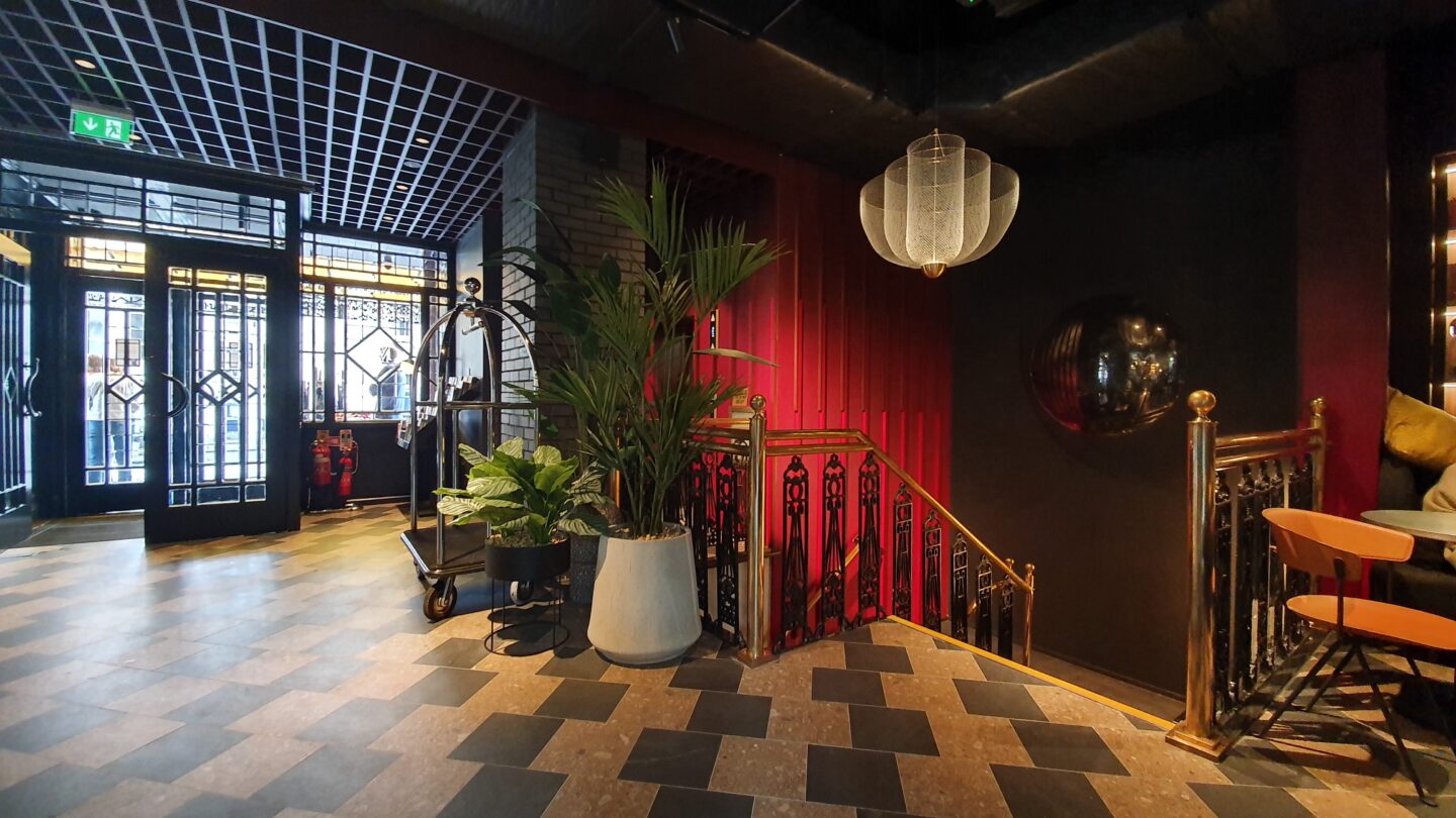 Interior shot of The Mont hotel, showing red walls, plants and tiled floors.