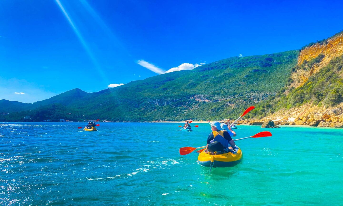 Lisbon travel guide must-doo activities. Photo shows kayak group with hilly scenery in the background.